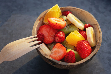 Wall Mural - Fruit salad in a natural bowl made from half a coconut shell on a metal tray