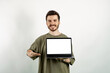 © platinumArt - Happy casual man wearing t-shirt posing isolated over white background holding laptop pc computer with blank empty screen.