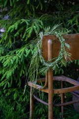 wild meadow flower wreath in the summer garden on the edge of a wooden chair. Summer solstice day, Midsummer concept. traditional floral decor. pagan witch traditions, wiccan symbol and rituals