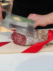 Canvas Print - person cutting salami delicatessen at buffet