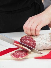 Canvas Print - person cutting salami delicatessen at buffet