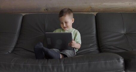 Young boy playing in a child development app on a digital tablet in a living room