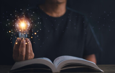 Wall Mural - Thinking and creative concept, Hand holding light bulb on the open book, Knowledge and searching for new ideas, Education, Innovations, self-learning, Inspiring from read.