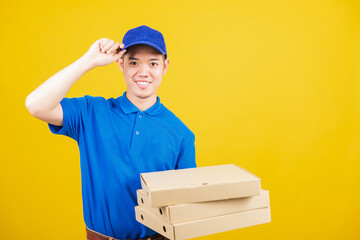 Wall Mural - Portrait excited delivery service man standing he smile wearing blue t-shirt and cap uniform hold give food order pizza cardboard boxes looking to camera, studio shot isolated on yellow background