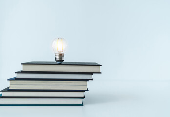 Wall Mural - Glowing lightbulb or bright lamp with book or textbook. Skill improvement for student or businessperson. Studying and training course online at home. Business success idea, education learning concept