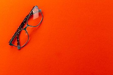 Wall Mural - Stylish eyeglasses over orange background. Glasses selection, eye test, vision examination at optician, fashion accessories concept. Top view, flat lay.