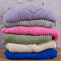 Wall Mural - six colored knitted sweaters, lie one on top of the other, against the background of a gray wall