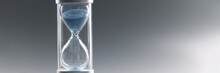 Closeup Of Hourglass With Blue Sand On Gray Background