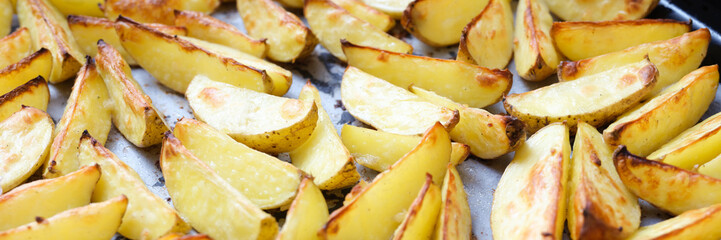 Baked potatoes lying on cooking paper on baking sheet closeup background