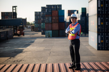 Owner of an import-export business standing on the container which shipping port area are loading container at commercial dock cargo freight shipping, container shipment warehouse is global business.