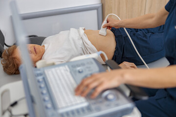 Wall Mural - Close up of doctor ultrasound examine senior patient abdomen at hospital. Prenatal diagnosis center