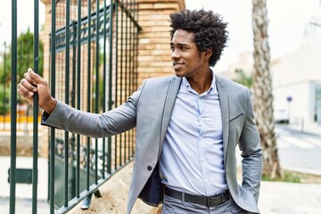 Wall Mural - Young african american businessman smiling happy standing at the city.