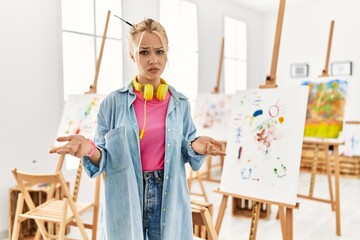 Poster - Young caucasian girl at art studio clueless and confused with open arms, no idea concept.