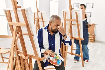 Canvas Print - Senior artist man at art studio tired rubbing nose and eyes feeling fatigue and headache. stress and frustration concept.