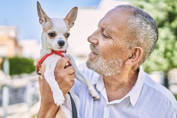 Canvas Print - Senior man smiling confident hugging chihuahua at street