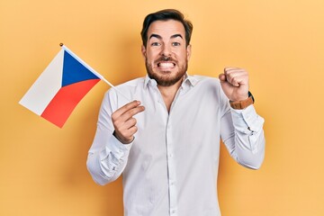 Wall Mural - Handsome caucasian man with beard holding czech republic flag screaming proud, celebrating victory and success very excited with raised arm