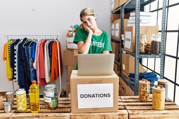 Poster - Young blonde woman wearing volunteer t shirt at donations stand thinking looking tired and bored with depression problems with crossed arms.