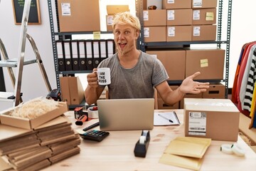 Poster - Young blond man drinking coffee working at online shop celebrating achievement with happy smile and winner expression with raised hand