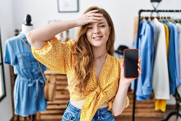 Canvas Print - Young caucasian woman at retail shop using smartphone stressed and frustrated with hand on head, surprised and angry face