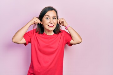 Canvas Print - Middle age hispanic woman wearing casual clothes smiling pulling ears with fingers, funny gesture. audition problem