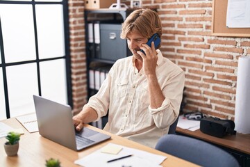 Poster - Young man business worker using laptop talking on smartphone at office