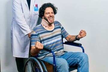 Sticker - Handsome hispanic man sitting on wheelchair wearing neck collar very happy and excited doing winner gesture with arms raised, smiling and screaming for success. celebration concept.