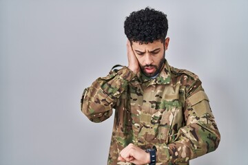 Sticker - Arab man wearing camouflage army uniform looking at the watch time worried, afraid of getting late