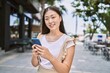 © Krakenimages.com - Young chinese girl smiling happy using smartphone at the city.