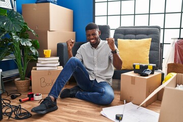 Poster - African american man sitting on the floor at new home excited for success with arms raised and eyes closed celebrating victory smiling. winner concept.