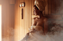 Young Woman Relaxing And Sweating In Hot Sauna Wrapped In Towel. Girl In Sauna. Interior Of Finnish Sauna, Classic Wooden Sauna With Hot Steam. Russian Bathroom. Relax In Hot Sauna With Steam