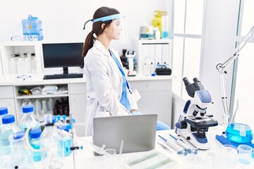 Poster - Young hispanic woman wearing scientist uniform looking to side, relax profile pose with natural face with confident smile.