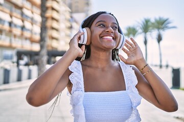 Wall Mural - Young african american girl smiling happy listening to music at the promenade.