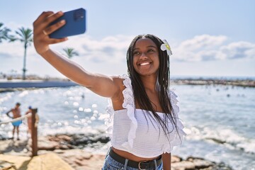 Sticker - Young african american girl smiling happy make selfie by the smartphone at the beach.