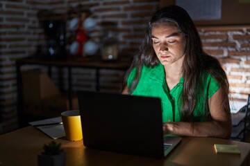 Sticker - Young teenager girl working at the office at night relaxed with serious expression on face. simple and natural looking at the camera.