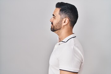 Sticker - Young hispanic man with beard wearing casual clothes over white background looking to side, relax profile pose with natural face and confident smile.