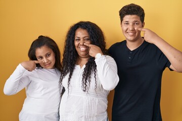 Sticker - Family of mother, daughter and son standing over yellow background pointing with hand finger to face and nose, smiling cheerful. beauty concept