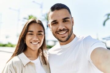 Canvas Print - Young latin couple smiling happy and hugging making selfie by the camera at the city.