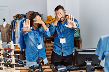 Wall Mural - Young interracial people working at retail boutique covering eyes with hands and doing stop gesture with sad and fear expression. embarrassed and negative concept.