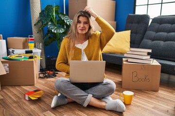 Sticker - Young woman sitting on the floor at new home using laptop confuse and wonder about question. uncertain with doubt, thinking with hand on head. pensive concept.