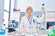 © Krakenimages.com - Young blonde woman wearing scientist uniform holding bottle at laboratory