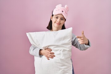 Sticker - Woman with down syndrome wearing sleeping mask hugging pillow cheerful with a smile on face pointing with hand and finger up to the side with happy and natural expression