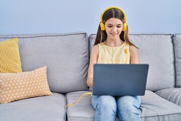 Sticker - Adorable girl using laptop sitting on sofa at home