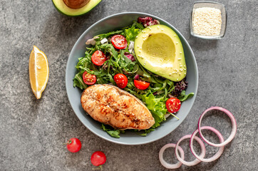 Wall Mural - grilled salmon steak and fresh green vegetable tomato salad with lettuce and avocado on stone background