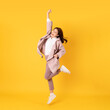 canvas print picture - happy asian woman white shirt and blazer on yellow background jumping