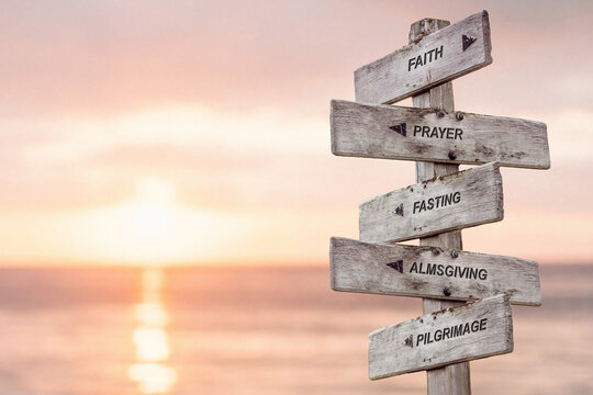 Wall Mural - faith prayer fasting almsgiving pilgrimage text engraved on wooden signpost by the ocean during sunset. five pillars of islam.