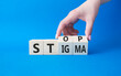 Stop and Stigma symbol. Concept words Stop and Stigma on wooden cubes. Beautiful blue background. Businessman hand. Business and Stop and Stigma concept. Copy space.