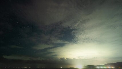 Wall Mural - 4K Time Lapse Stars Starry Night Sky Milky Way in Bali Indonesia, Clouds Moving and City Light