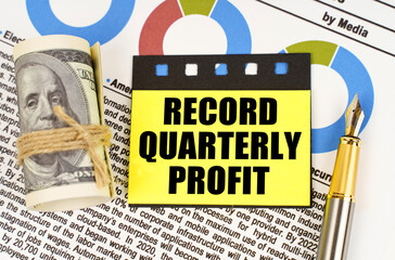 Poster - On documents with diagrams there are dollars, a pen and yellow stickers with the inscription - Record quarterly profit