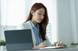 © Jirapong - Portrait of a young businesswoman or business owner working with a notebook and tablet computer at office room