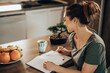 Woman Making To Do List While Enjoying Morning Coffee At Home
